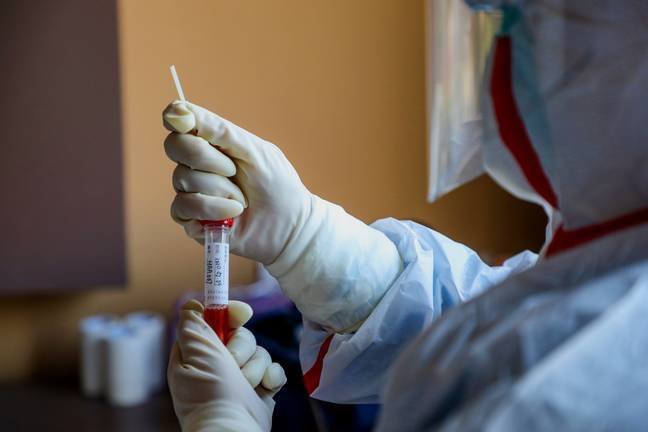 This photo taken on February 4, 2020 shows a medical staff member collecting a sample taken from a person to be tested for the new coronavirus at a quarantine zone in Wuhan, the epicentre of the outbreak, in China's central Hubei province. - The world has a "window of opportunity" to halt the spread of a deadly new virus, global health experts said, as the number of people infected in China jumped to 24,000 and millions more were ordered to stay indoors. (Photo by STR / AFP) / China OUT