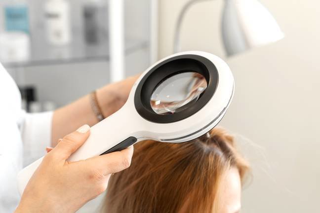 A trichologist examines the condition of the hair on the patients head with a dermatoscope. In a bright cosmetology room.