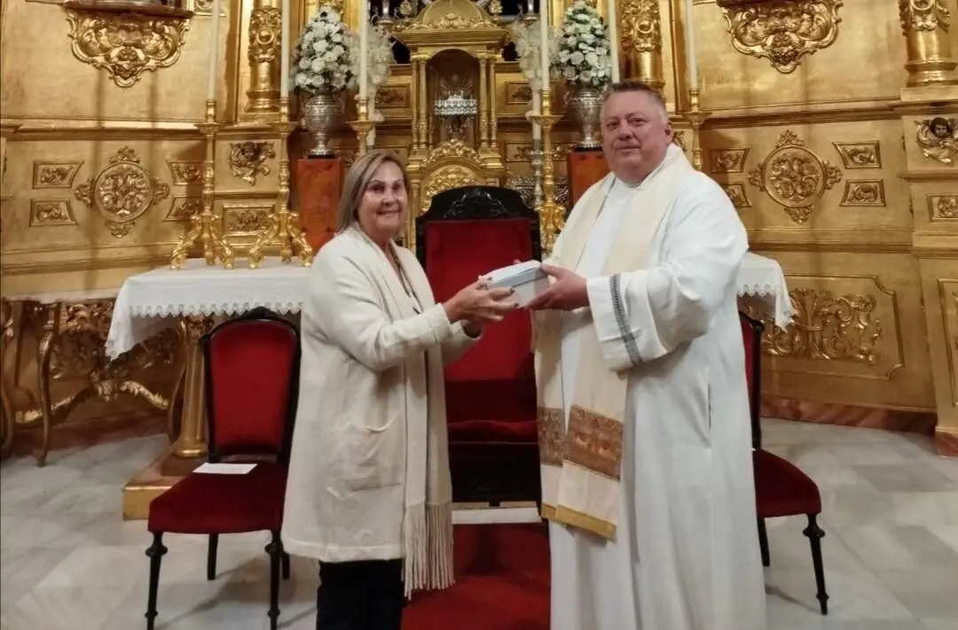 Pili Quesada recibe del párroco Gregorz Korza la mano de la virgen