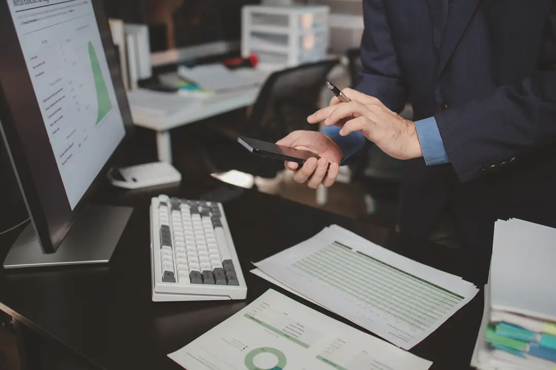 Asian male businessman working in the room. Startup company employee is pressing smartphone to view information, he is in office at night, working overtime, lots of work, hard work. Overtime concept.