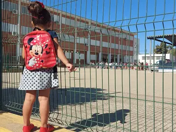 Una pequeña observa el pario de un colegio en la capital