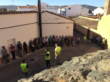 Colada de lava, en primer término y visitantes a la actividad geológica
