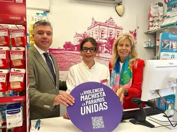 l presidente del Colegio de Farmacéuticos de Huelva, Jorge J. García Maestre, y la subdelegada del Gobierno en Huelva, María José Rico, con el distintivo de 'Punto violeta' en una oficina de farmacia onubense.