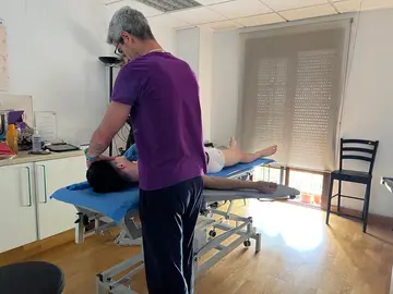 Un fisioterapeuta da una sesión a un paciente