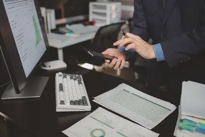 Asian male businessman working in the room. Startup company employee is pressing smartphone to view information, he is in office at night, working overtime, lots of work, hard work. Overtime concept.