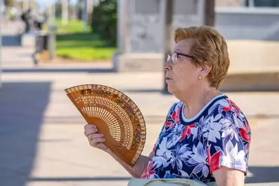 Una mujer soporta el calor abanic&aacute;ndose.