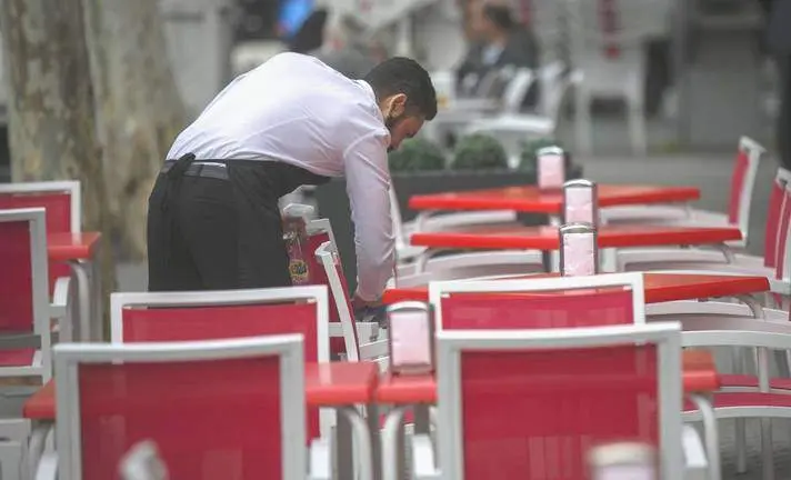 Un camarero ordena las sillas en una terraza