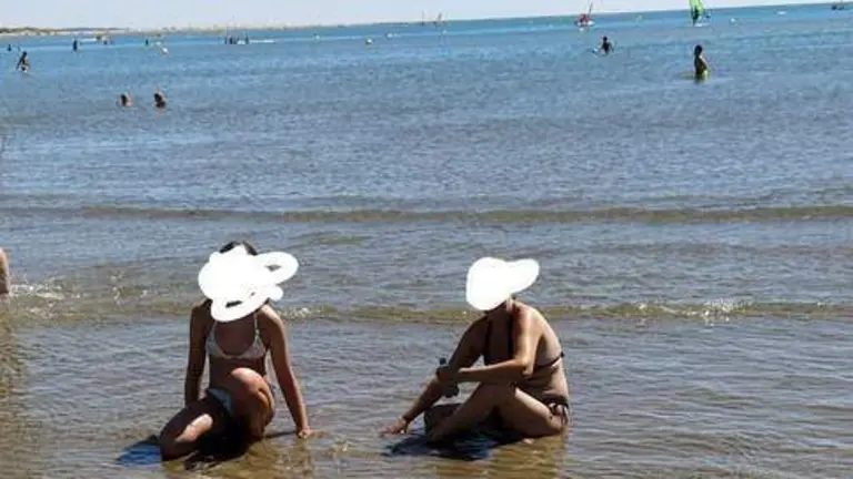 Dos mujeres recogen coquinas en la orilla