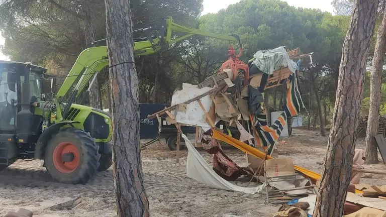 Las gr&uacute;as destruyen y retiran los restos de las chabolas dentro de los asentamientos en el monte