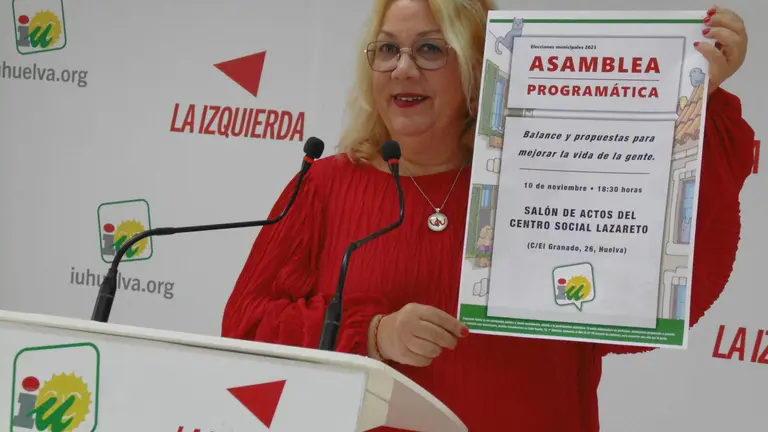 Mónica Rossi muestra el cartel de la Asamblea programática de IU Huelva