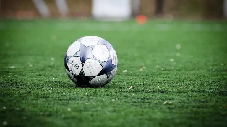 Balón de fútbol blanco y azul en el campo de hierba verde durante el día