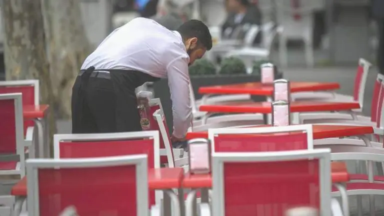 Un camarero ordena las sillas en una terraza