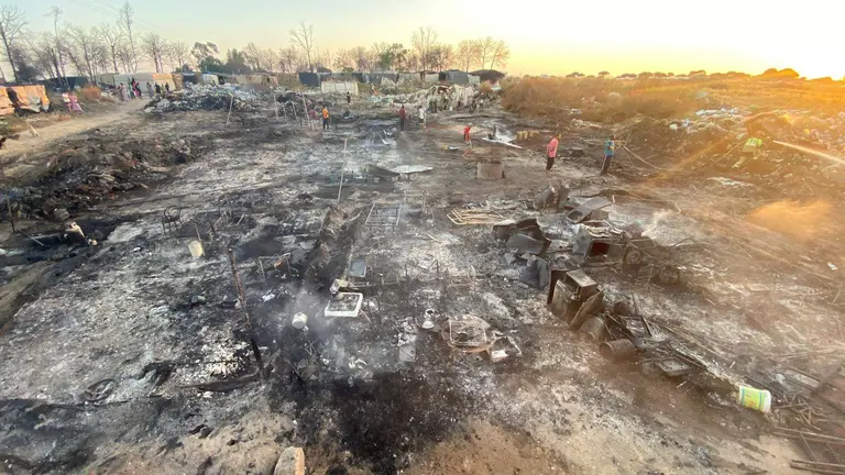 Residentes buscan sus pertenencias tras el fuego que devor&oacute; el campamento