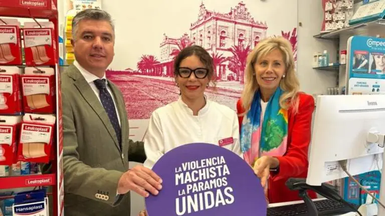 l presidente del Colegio de Farmacéuticos de Huelva, Jorge J. García Maestre, y la subdelegada del Gobierno en Huelva, María José Rico, con el distintivo de 'Punto violeta' en una oficina de farmacia onubense.