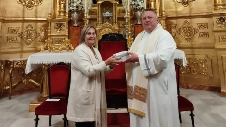 Pili Quesada recibe del párroco Gregorz Korza la mano de la virgen