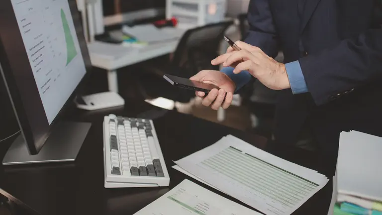 Asian male businessman working in the room. Startup company employee is pressing smartphone to view information, he is in office at night, working overtime, lots of work, hard work. Overtime concept.