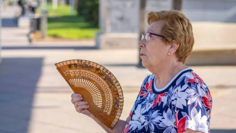 Una mujer soporta el calor abanic&aacute;ndose.