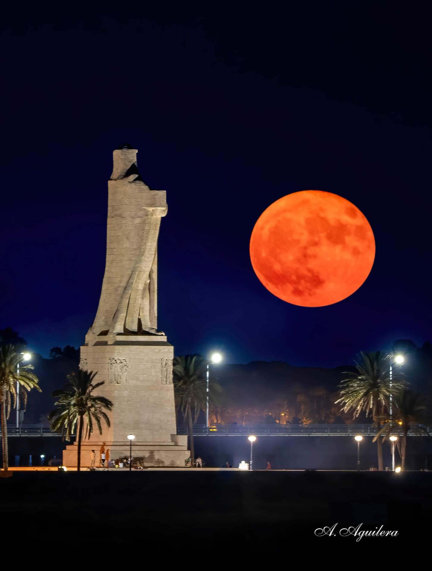 La luna llena, a su paso por el Monumento a Colón.