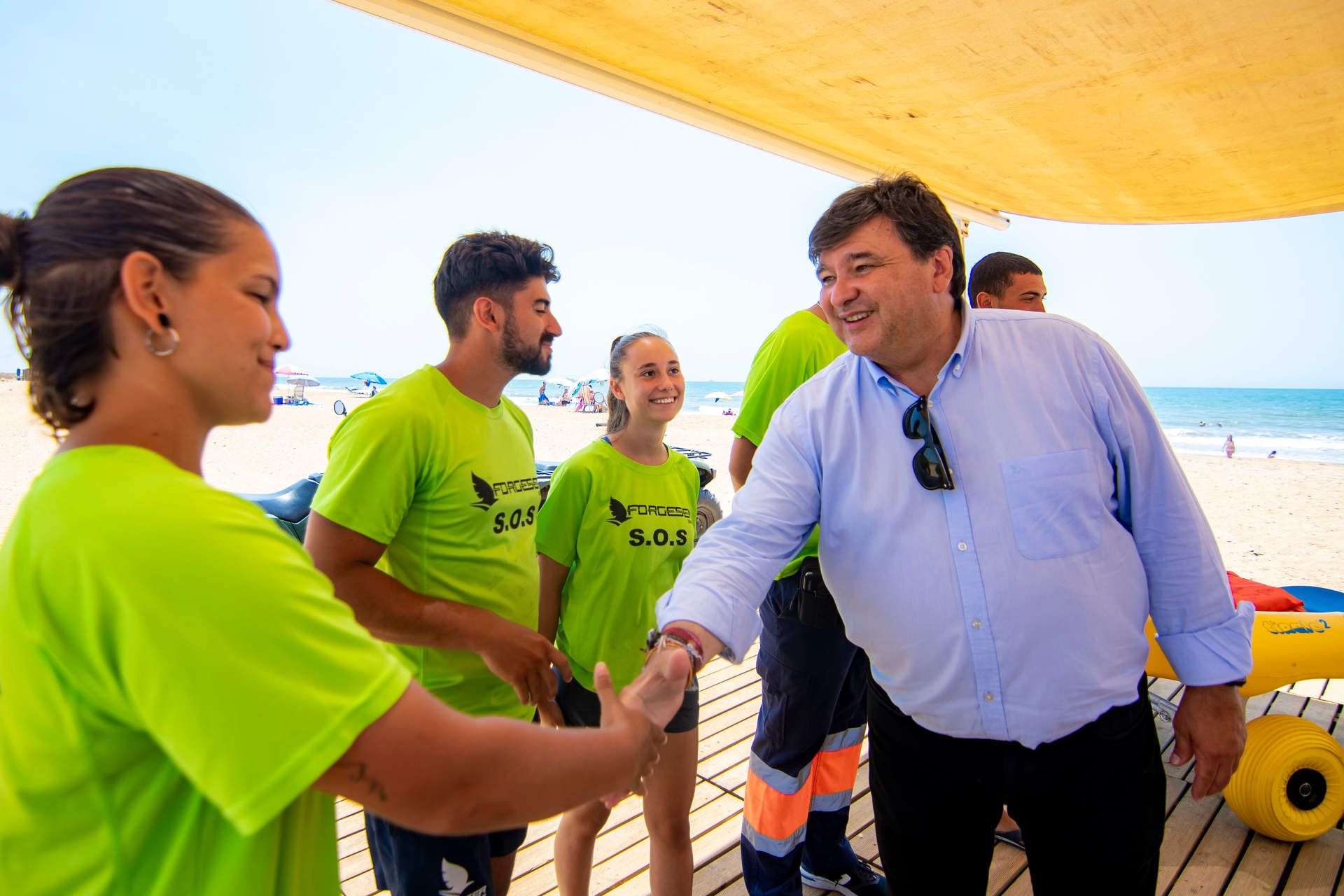 El alcalde, durante el izado de las banderas, saluda al personal de la playa.